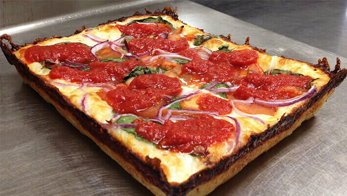 Detroit-style Pizza, a rectangular shaped pizza with tomato sauce and meat